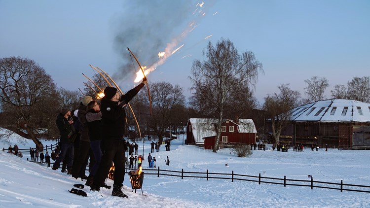 Pilbågsskyttar skjuter brinnande pilar i ett snöigt landskap