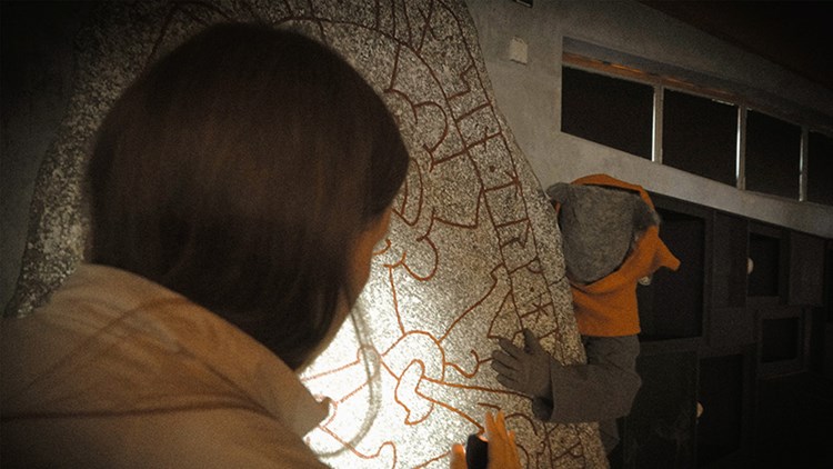 Peron i mask gömmer sig bakom en runsten