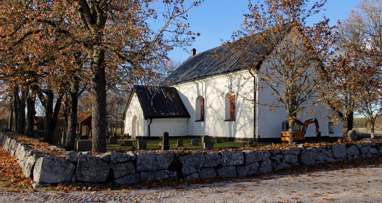Vit gammal kyrka omgärdad av en stenmur